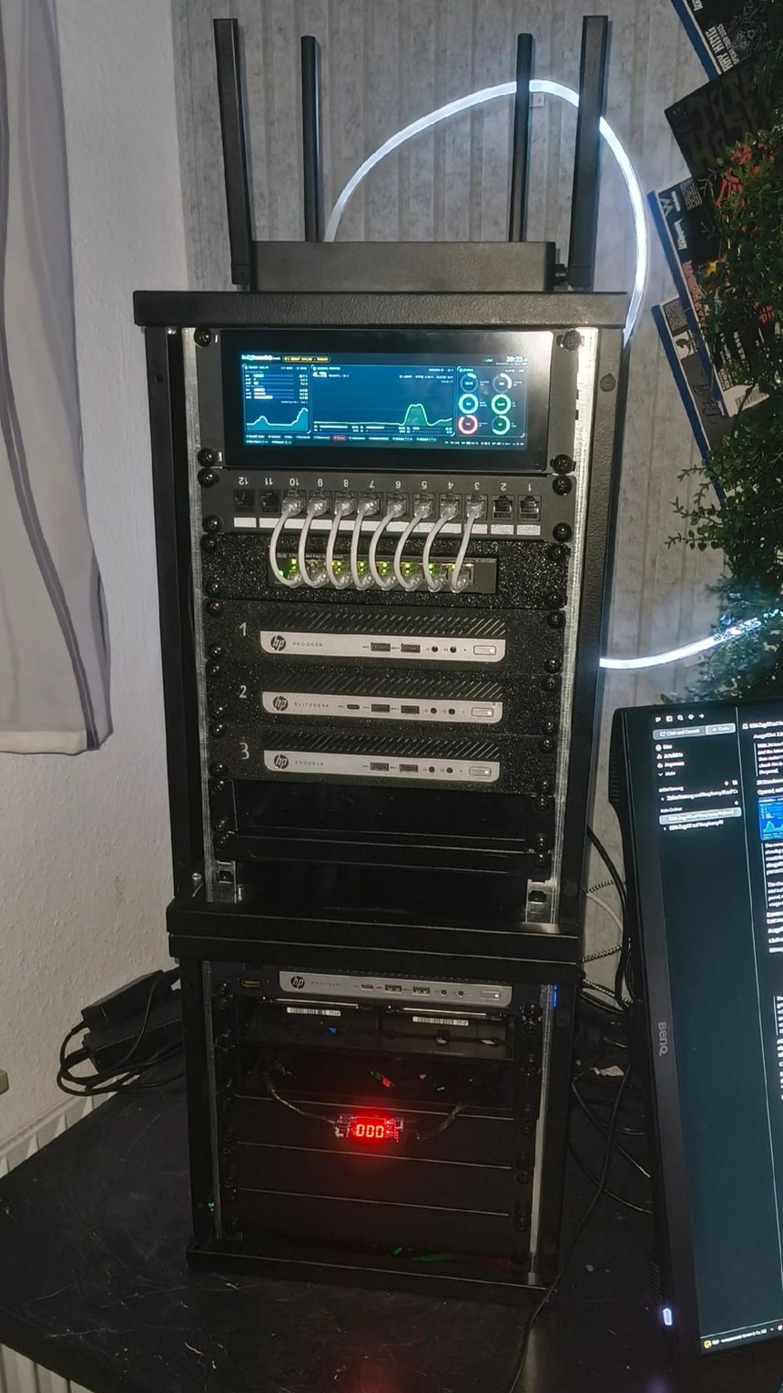 Das Rack von vorn: oben der Router, darunter ein Display mit dem laufenden Statusbild, ein Patchfeld und die nummerierten Rechner