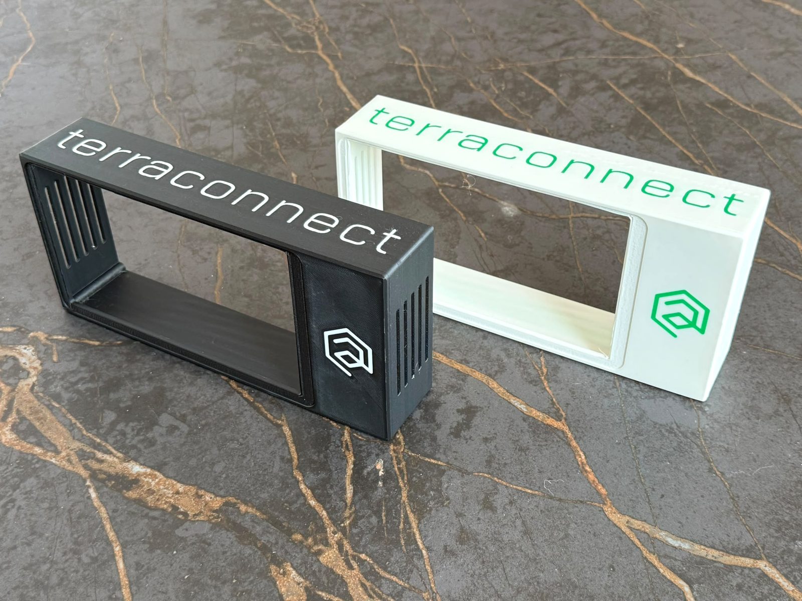 Zwei 3D-gedruckte Gehäuse-Varianten in Schwarz und Weiß mit TerraConnect-Branding